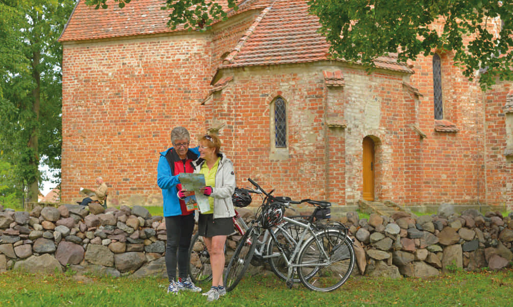 Fahrradfahrer vor der Kirche in Ludorf, Mecklenburgische Seenplatte